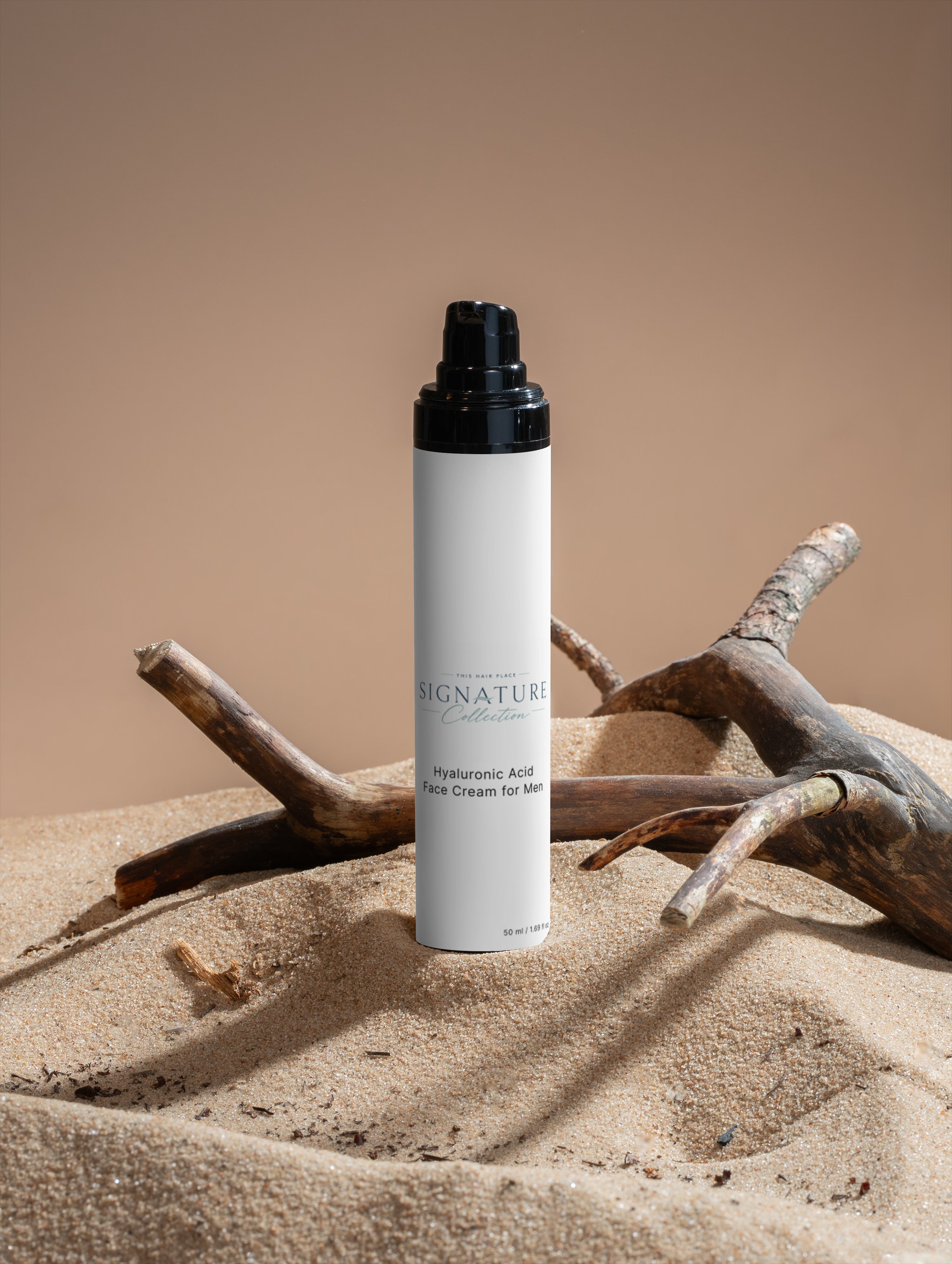 Skincare bottle labeled 'Signature' on a sandy surface with driftwood.